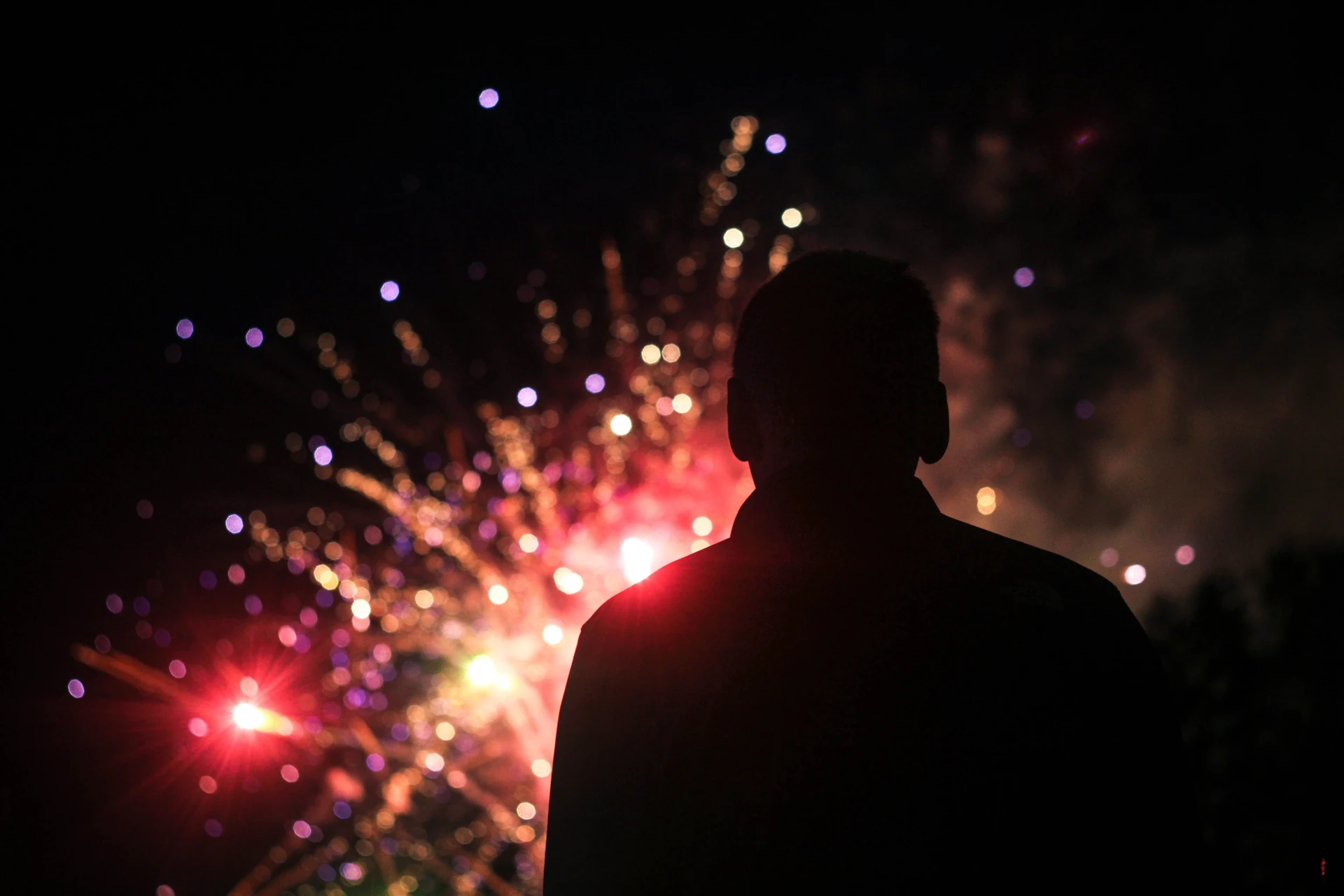 Silhouette of man infront of exploding fireworks.